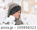 a boy is playing with snow on the street, it is snowing, a blizzard and frost on a winter day 109898323