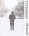 A boy walks along a snowy street, it is snowing, blizzard and frost on a winter day 109898325