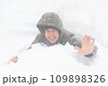 a boy lies in the snow, on a snowy street, it is snowing, a blizzard and frost on a winter day 109898326