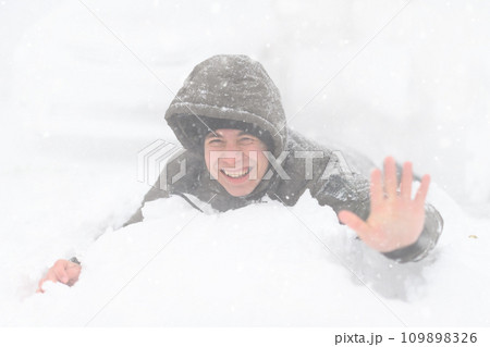 a boy lies in the snow, on a snowy street, it is snowing, a blizzard and frost on a winter day 109898326