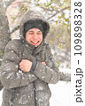 a boy is posing with snow on the street, it is snowing, a blizzard and frost on a winter day 109898328