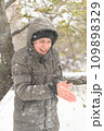 a boy is posing with snow on the street, it is snowing, a blizzard and frost on a winter day 109898329