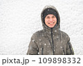 a boy is posing on snow background outdoor, it is snowing, a blizzard and frost on a winter day 109898332