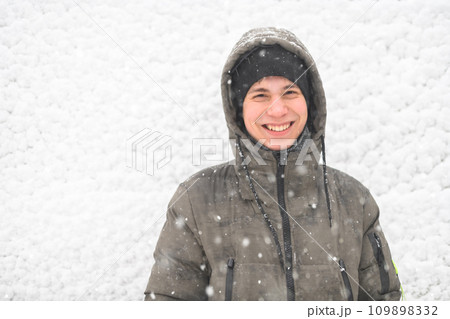 a boy is posing on snow background outdoor, it is snowing, a blizzard and frost on a winter day 109898332