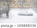a girl is playing with snow on the street, making snowman, it is snowing, a blizzard and frost on a winter day 109898336