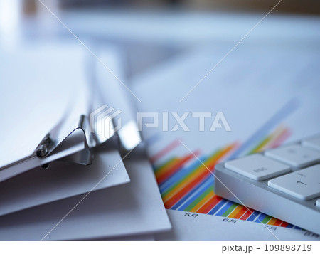 テーブルに置かれたグラフと書類とキーボード 109898719