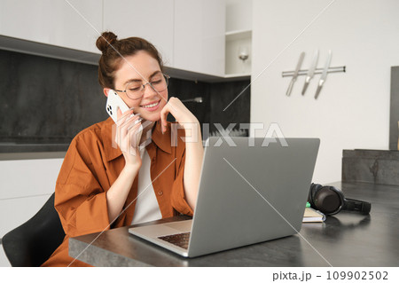 Portrait of woman working or studying at home, using laptop and mobile phone 109902502