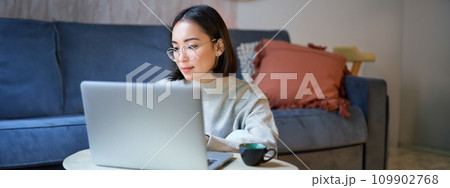 Self employed young korean woman working on remote, typing on laptop, studying at home in living room 109902768