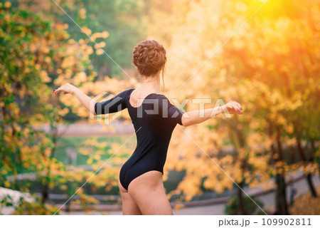 Beautiful female, ballerina, athlete in black bodysuit training in the park 109902811