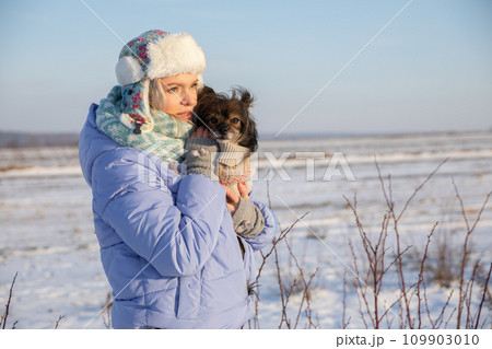 An owner on a winter walk needs to keep her dog warm. An owner on a winter walk needs to keep her dog warm. 109903010