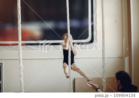 Coach with student. Girls gymnasts, performs various gymnastic exercises and jumping. Childs and sport, a healthy lifestyle. Coach with student. Girls gymnasts, performs various gymnastic exercises and jumping. Childs and sport, a healthy lifestyle. 109904138