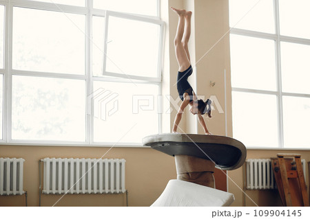 Child gymnastics balance beam. Girl gymnast athlete during an exercise horizontal bar in gymnastics competitions. 109904145