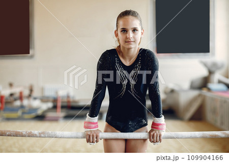 Child gymnastics balance beam. Girl gymnast athlete during an exercise horizontal bar in gymnastics competitions. 109904166