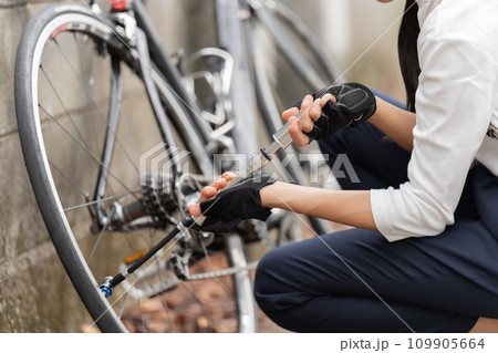 ロードバイクに 携帯用ポンプで空気を入れている若い女性 ロードバイクに 携帯用ポンプで空気を入れている若い女性 109905664