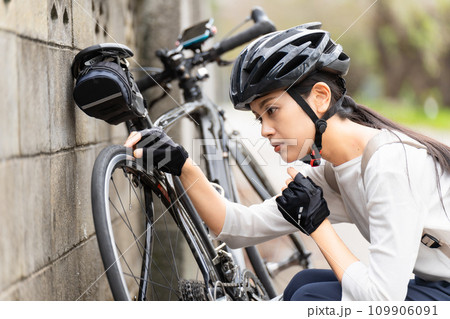 ロードバイクのパンクトラブルに困る若い女性 ロードバイクのパンクトラブルに困る若い女性 109906091