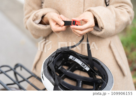 サイクリングヘルメットのあご紐の長さを調整している若い女性 109906155