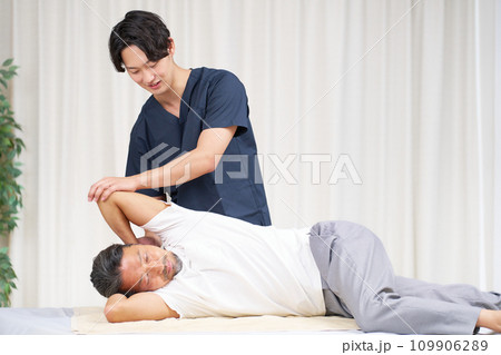 男性に施術を行う若い整体師 109906289