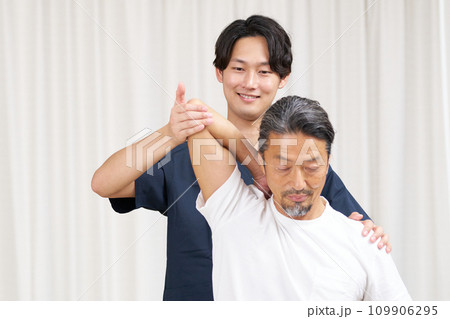 高齢男性に施術を行うあん摩マッサージ指圧師 109906295