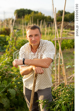 Male farmer farmer with rake standing at farm outdoor 109906390