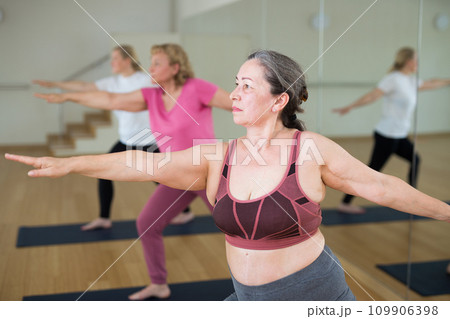Aged women are exercising warrior II pose 109906398