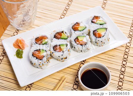 On table there is plate with set of sushi - uramaki rolls california roll with chees On table there is plate with set of sushi - uramaki rolls california roll with chees 109906503
