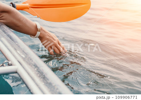 Woman in kayak back view. Happy young woman with long hair floating in transparent kayak on the crystal clear sea. Summer holiday vacation and cheerful female people relaxing having fun on the boat Woman in kayak back view. Happy young woman with long hair floating in transparent kayak on the crystal clear sea. Summer holiday vacation and cheerful female people relaxing having fun on the boat 109906771