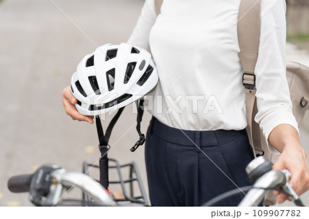 ママチャリの横でヘルメットを抱えてる若い女性　パーツカット 109907782
