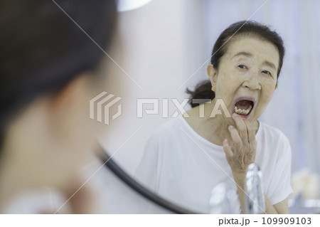 鏡の前で口の中を気にするシニア女性 109909103