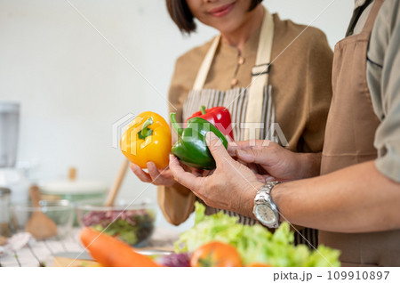 A lovely adult couple cooking in the kitchen together, preparing fresh vegetables and ingredients. 109910897