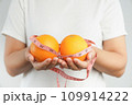 Hand holding fresh organic orange fruit and measure tape. 109914222