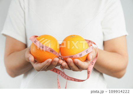 Hand holding fresh organic orange fruit and measure tape. 109914222