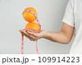 Hand holding fresh organic orange fruit and measure tape. 109914223
