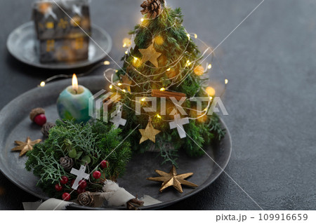 小さなクリスマスツリーのイルミネーションとキャンドル 109916659