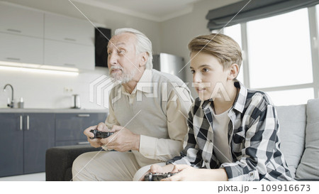 Active grandpa playing video game with his teenage grandson, having fun together Active grandpa playing video game with his teenage grandson, having fun together 109916673