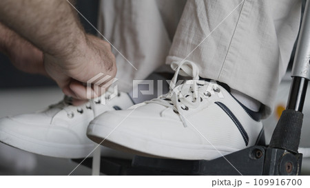 Close-up of nurse tying shoelaces of person in wheelchair, assisted living facility Close-up of nurse tying shoelaces of person in wheelchair, assisted living facility 109916700