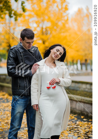 A man hugs his pregnant wife. Woman holding baby's socks near belly A man hugs his pregnant wife. Woman holding baby's socks near belly 109916920