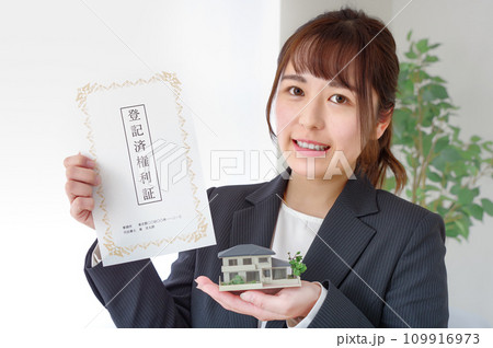 不動産の権利書と住宅模型を持つ女性 109916973