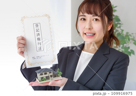 不動産の権利書と住宅模型を持つ女性 109916975