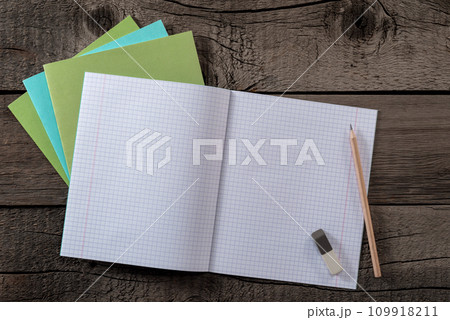 School Notebook with Millimeter Grid Pages and Pencil with Eraser on Old Wooden Surface. File with Clipping Path. School Notebook with Millimeter Grid Pages and Pencil with Eraser on Old Wooden Surface. File with Clipping Path. 109918211