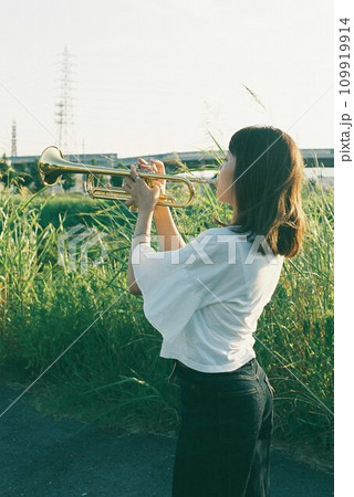 公園でトランペットを吹く女性の後ろ姿 109919914