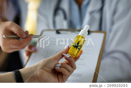 Visitor hand holding jar of cannabis concentrate oil Visitor hand holding jar of cannabis concentrate oil 109920203
