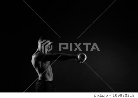 Young man with dumbbells good physique isolated on red and black background. Strength and motivation Young man with dumbbells good physique isolated on red and black background. Strength and motivation 109920218