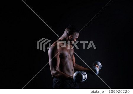 Young man with dumbbells good physique isolated on red and black background. Strength and motivation 109920220