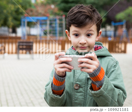 Boy holding smartphone outdoors in autumn 109921181