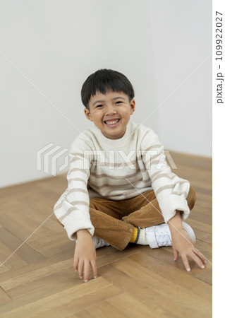 あぐらで座る小学1年生の男の子　カメラ目線で笑顔のポートレート 109922027