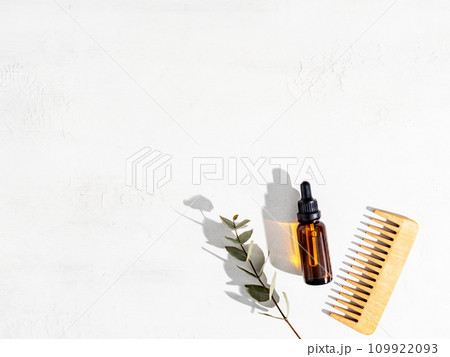 Essential oil for hair care with wooden hair comb on white background Essential oil for hair care with wooden hair comb on white background 109922093
