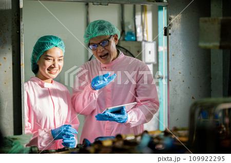 Two machine engineers at the beverages factory engage in quality control discussions using a digital tablet. They focus on examining manufacturing processes in the drinks production plant. Two machine engineers at the beverages factory engage in quality control discussions using a digital tablet. They focus on examining manufacturing processes in the drinks production plant. 109922295