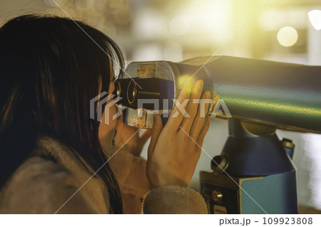 コイン式望遠鏡で夜景を楽しむ女性 109923808