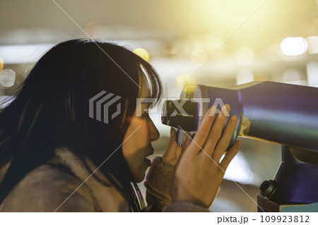 コイン式望遠鏡で夜景を楽しむ女性 109923812