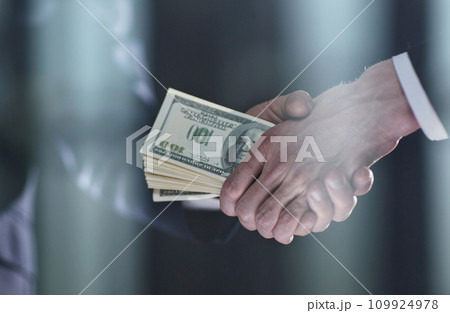 Handshake with the transfer of money on a black background Handshake with the transfer of money on a black background 109924978